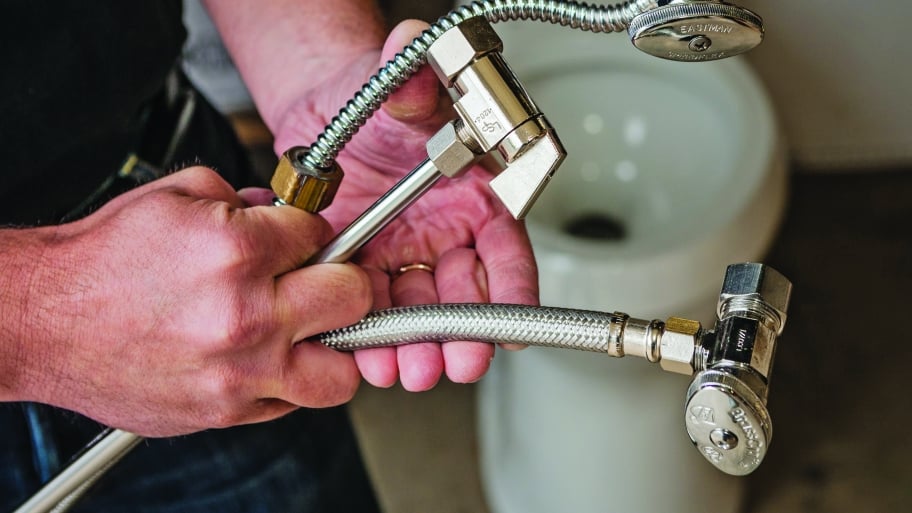A plumber holds plumbing fixtures.